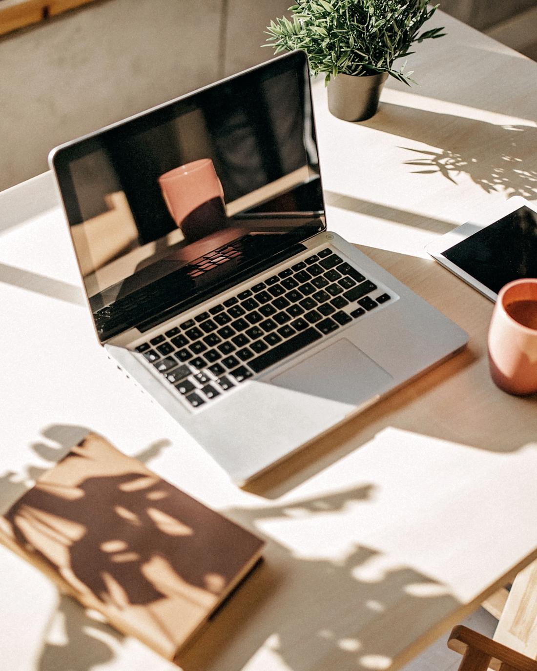 A calm, sunlit desk with a laptop and coffee